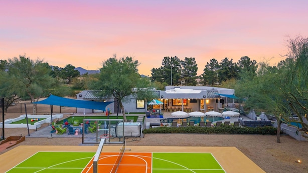 A tennis court with a net, surrounded by outdoor seating and a building with a patio. - Fun-filled Oasis Pool Pickleball Games Galore (Scottsdale)