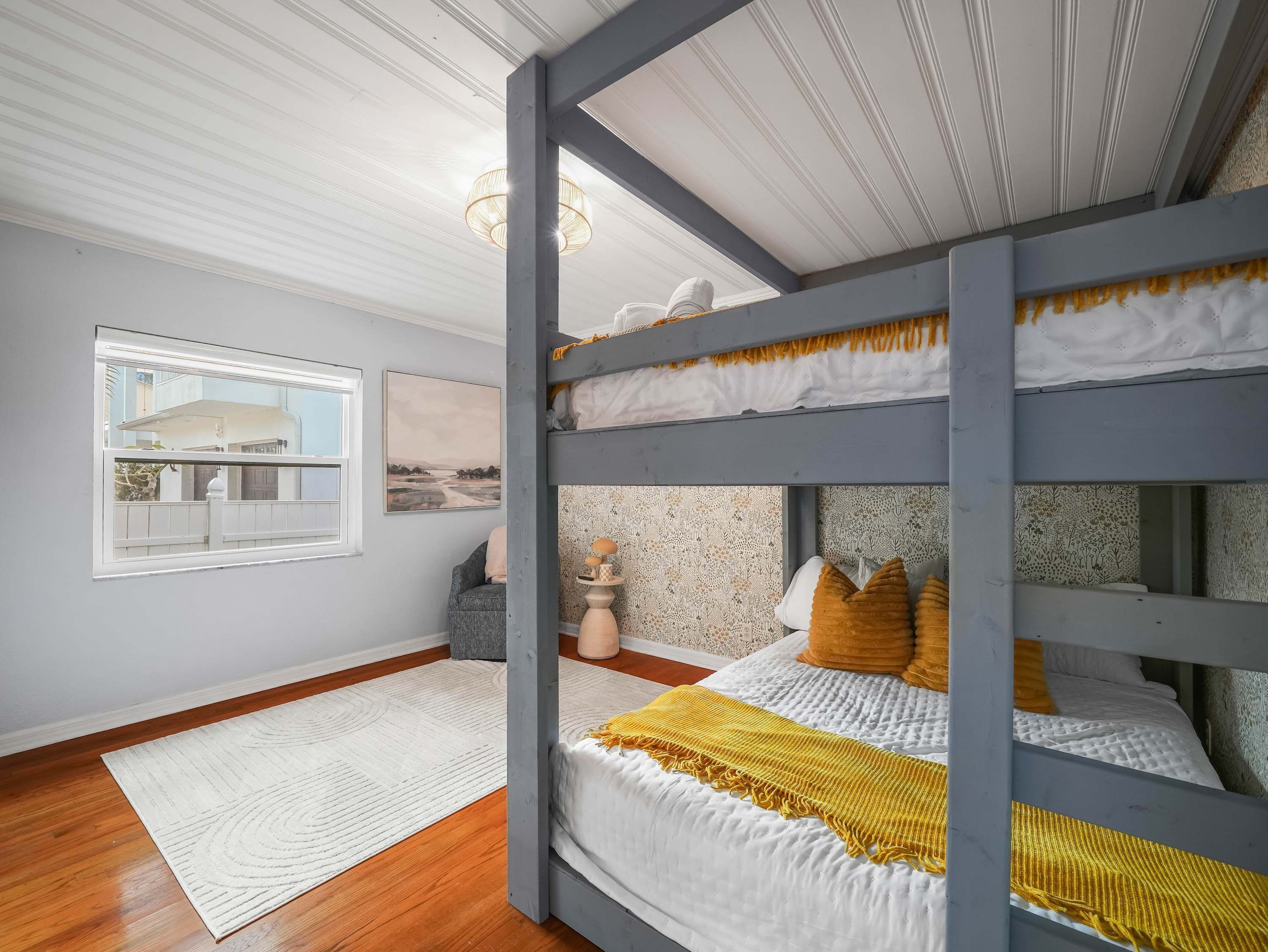 A room with a bunk bed, a window with a view, a rug, and a chair.