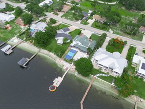 Vista aérea de una zona residencial con un muelle, una piscina y casas.