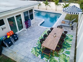 Un patio trasero con piscina, mobiliario de jardín y una zona de estar cubierta.