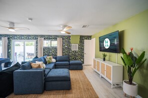 Una sala de estar moderna con un sofá modular, un televisor de pantalla plana y una planta grande en maceta.