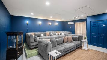 Una sala de estar moderna con un sofá seccional, una mesita auxiliar, un proyector y una pared azul.