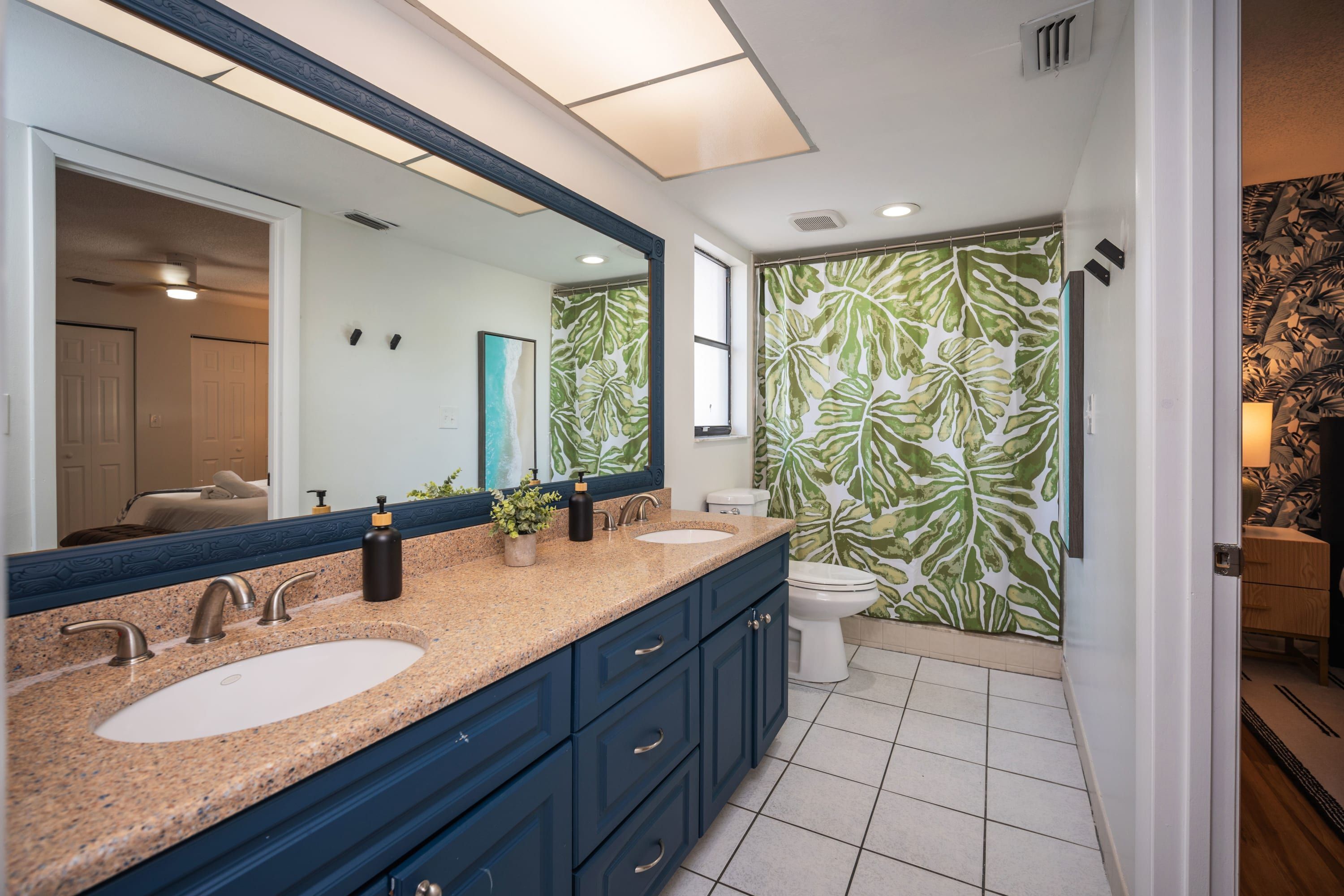 A bathroom with a double sink vanity, a large mirror, and a toilet.