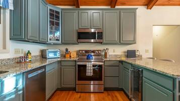 A kitchen with a stainless steel microwave, oven, and dishwasher, wooden cabinets, and a granite countertop.