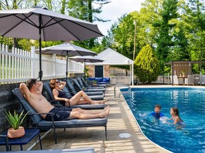A poolside area with lounge chairs, umbrellas, and a barbecue setup. - Wild West Pool Sportcourt Hot Tub Fire Pit (Candler)