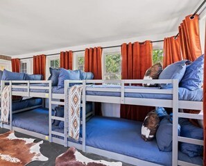 A room with bunk beds, orange curtains, and a cowhide rug. - Wild West Pool Sportcourt Hot Tub Fire Pit (Candler)