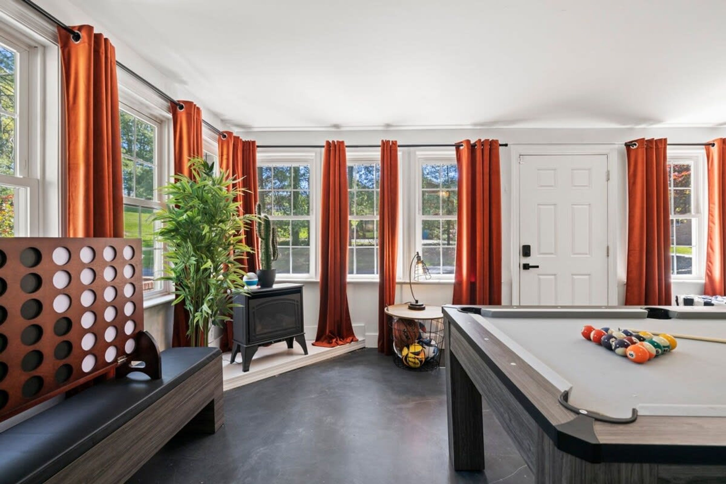 A room with a pool table, a bench, a potted plant, and a door.
