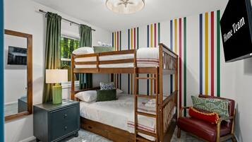 A bunk bed room with a desk, chair, and a TV on the wall.
