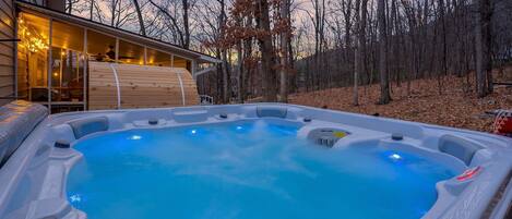 Un jacuzzi en un patio trasero con una terraza de madera y una casa al fondo.