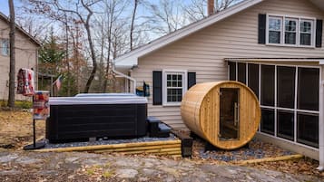 A house with a hot tub, a wooden barrel, and a stone pathway.