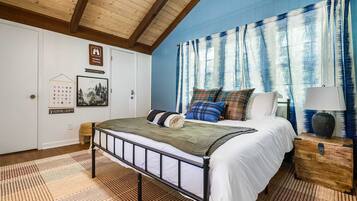 A bedroom with a bed, a nightstand, a lamp, and a window with curtains.