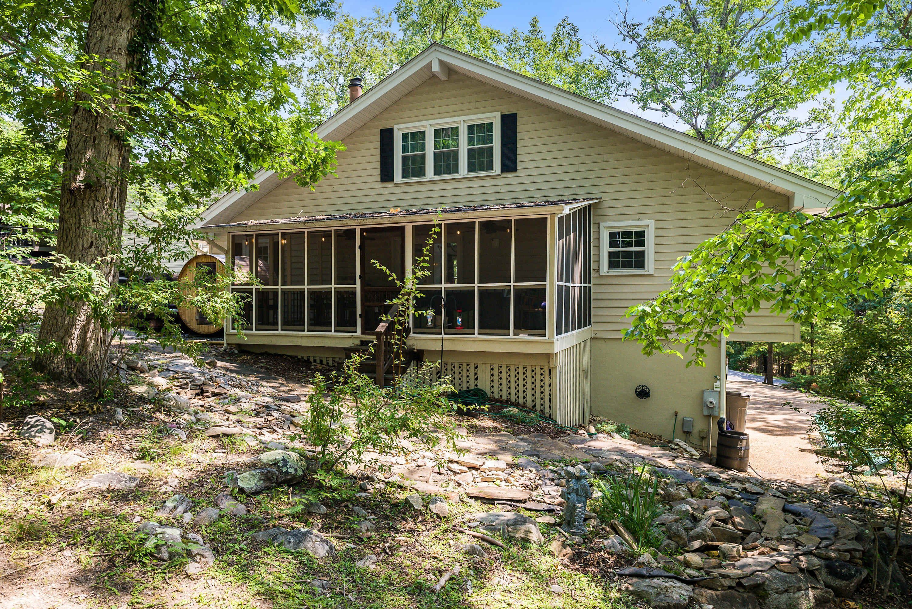 A single-story house with a covered porch, a stone pathway leading to the entrance, and a wooden barrel.