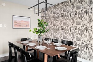 A dining area with a wooden table set for four, surrounded by black chairs, a potted plant, and a framed picture on the wall. - Heated Pool Hot Tub Game Room Sport Court (Glendale)