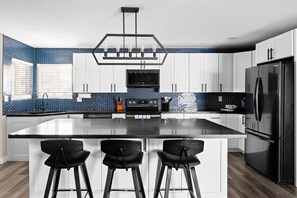 Una cocina moderna con un refrigerador negro, armarios blancos y un salpicadero de azulejos azules.