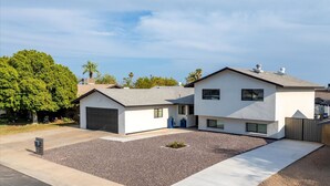 Uma casa residencial de dois andares com garagem, entrada por um caminho e um jardim frontal bem cuidado.