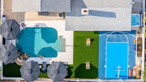 Vista aérea de uma propriedade com piscina, quadra de tênis e área de estar externa.