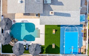 Ein Luftbild eines Anwesens mit Schwimmbad, Tennisplatz und Außenmöbeln.
