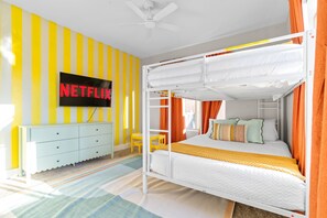 Ein Zimmer mit Etagenbett, Wandfernseher und einer gestreiften Wand.