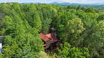 Une cabane entourée d’une forêt dense, avec un toit rouge, située dans une région montagneuse.
