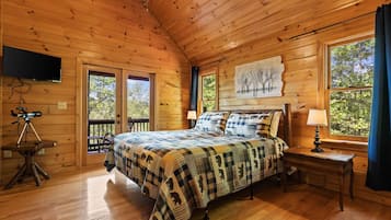 Une chambre dans une cabane en bois, avec un lit, un téléviseur fixé au mur et un télescope posé sur une table.