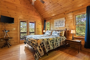 A wooden cabin bedroom with a bed, a mounted TV, and a telescope on a table. - Stunning Views Hot Tub Games Fireplace Dogfriendly (Morganton)