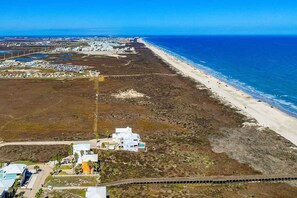 An aerial view of a coastal area with a beach, a parking lot, and a few buildings. - Amazing Beach Views Boardwalk to Beach Shared Pool (Port Aransas)