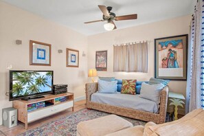 Ein Wohnzimmer mit Fernseher, Deckenventilator, Sofa und Couchtisch.
