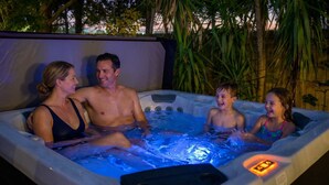 A family of four in a hot tub with a digital control panel. - Outdoor Movie Theatre Pool Putt Putt Hot Tub (Largo)