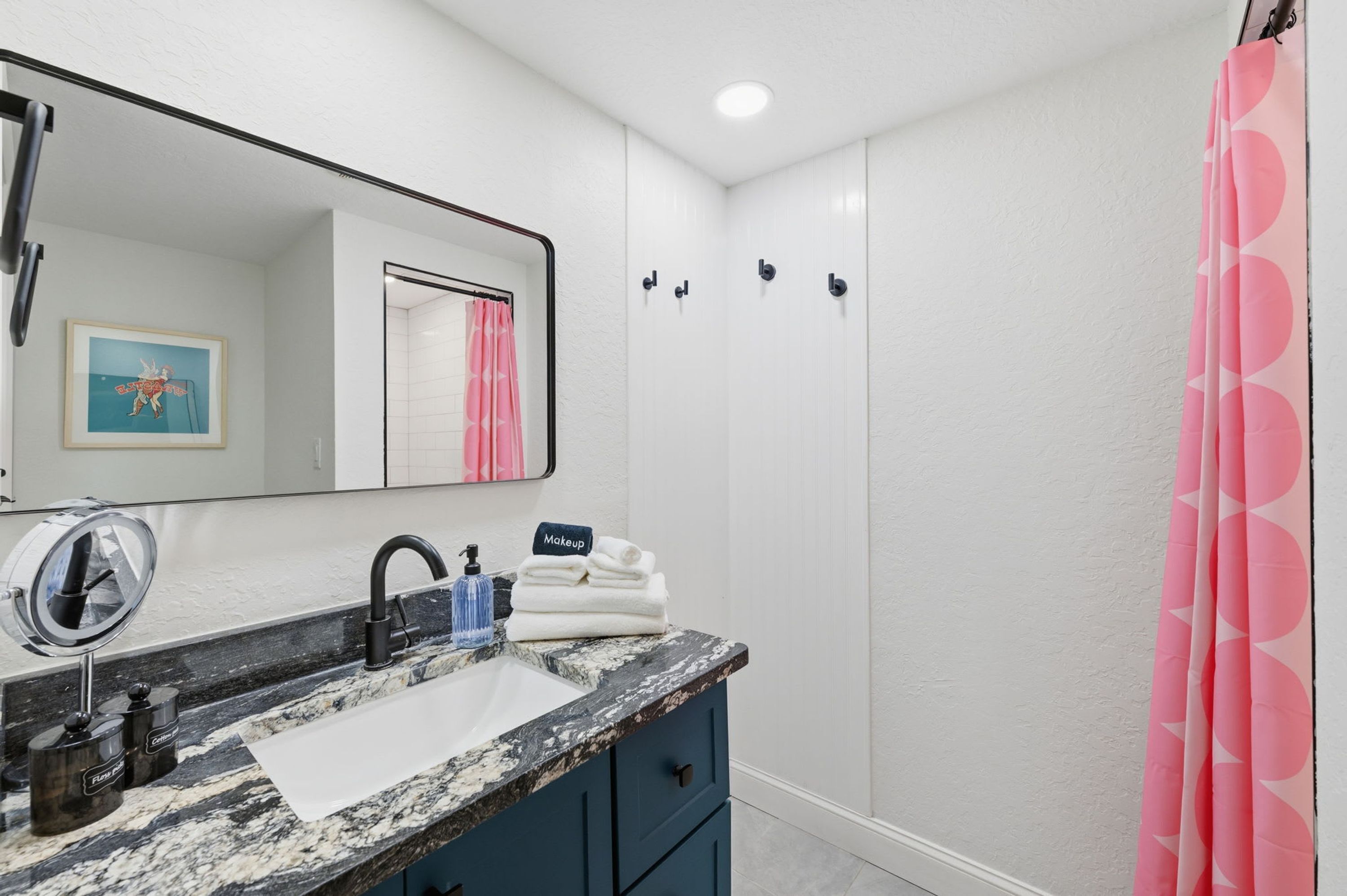 A bathroom with a white sink, a mirror, a shower curtain, and a towel rack.
