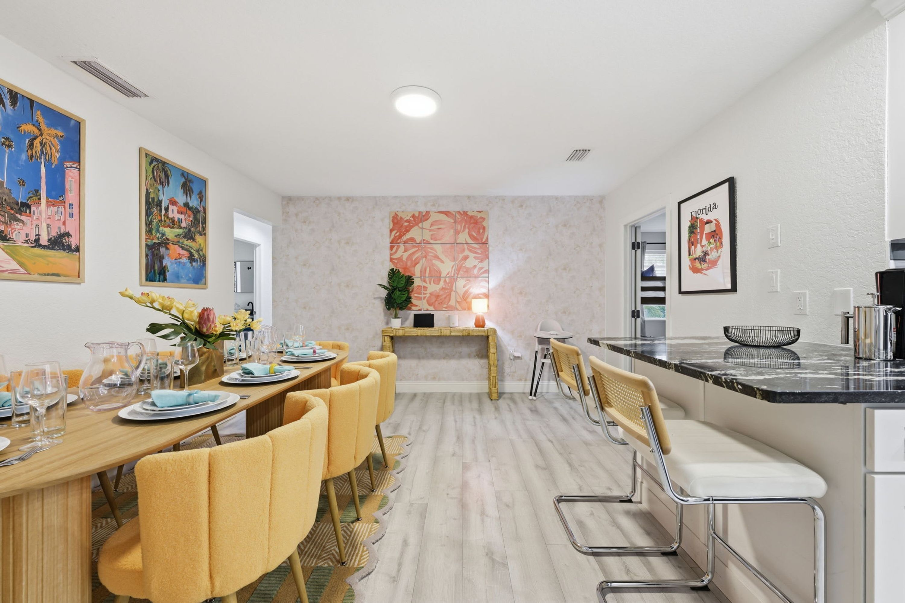 Une cuisine moderne avec un coin repas, comprenant un îlot central, des sièges de bar et une vue sur le salon.