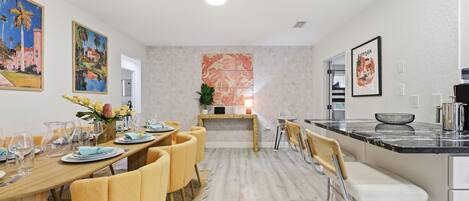 Une cuisine moderne avec un coin repas, comprenant un îlot central, des sièges de bar et une vue sur le salon.