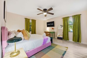 A hotel room with a bed, a desk, a chair, a ceiling fan, and a TV screen displaying 'Home Team'. - Outdoor Movie Theatre Pool Putt Putt Hot Tub (Largo)
