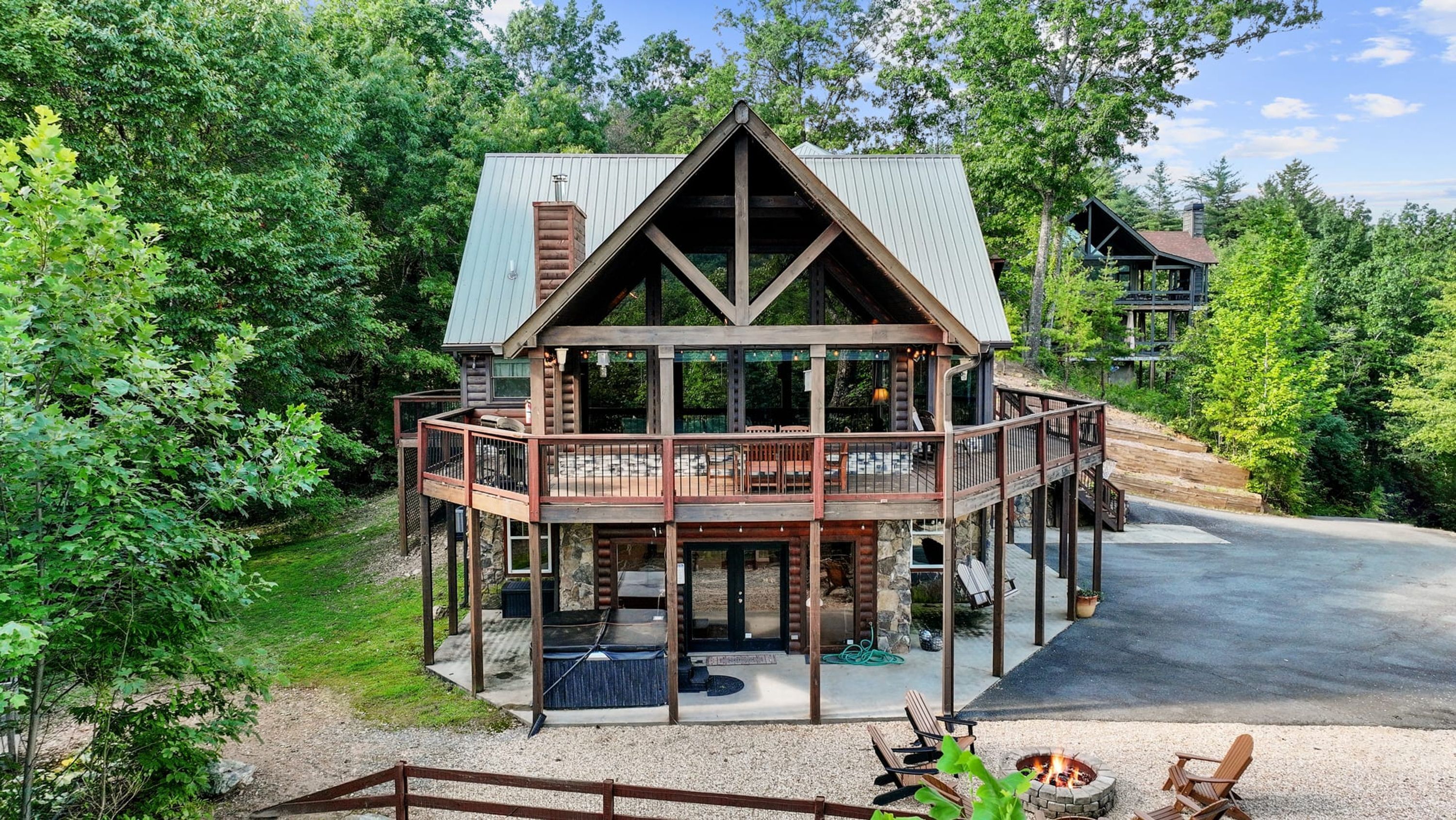 Eine zweigeschossige Holzblockhütte mit Balkon und Sitzbereich im Freien.