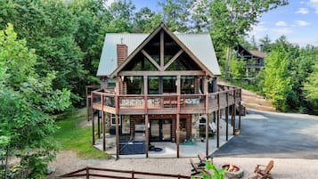 A two-story log cabin with a balcony and outdoor seating area.