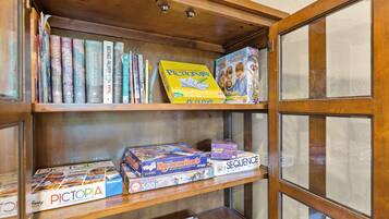 A wooden bookshelf with various books and board games.
