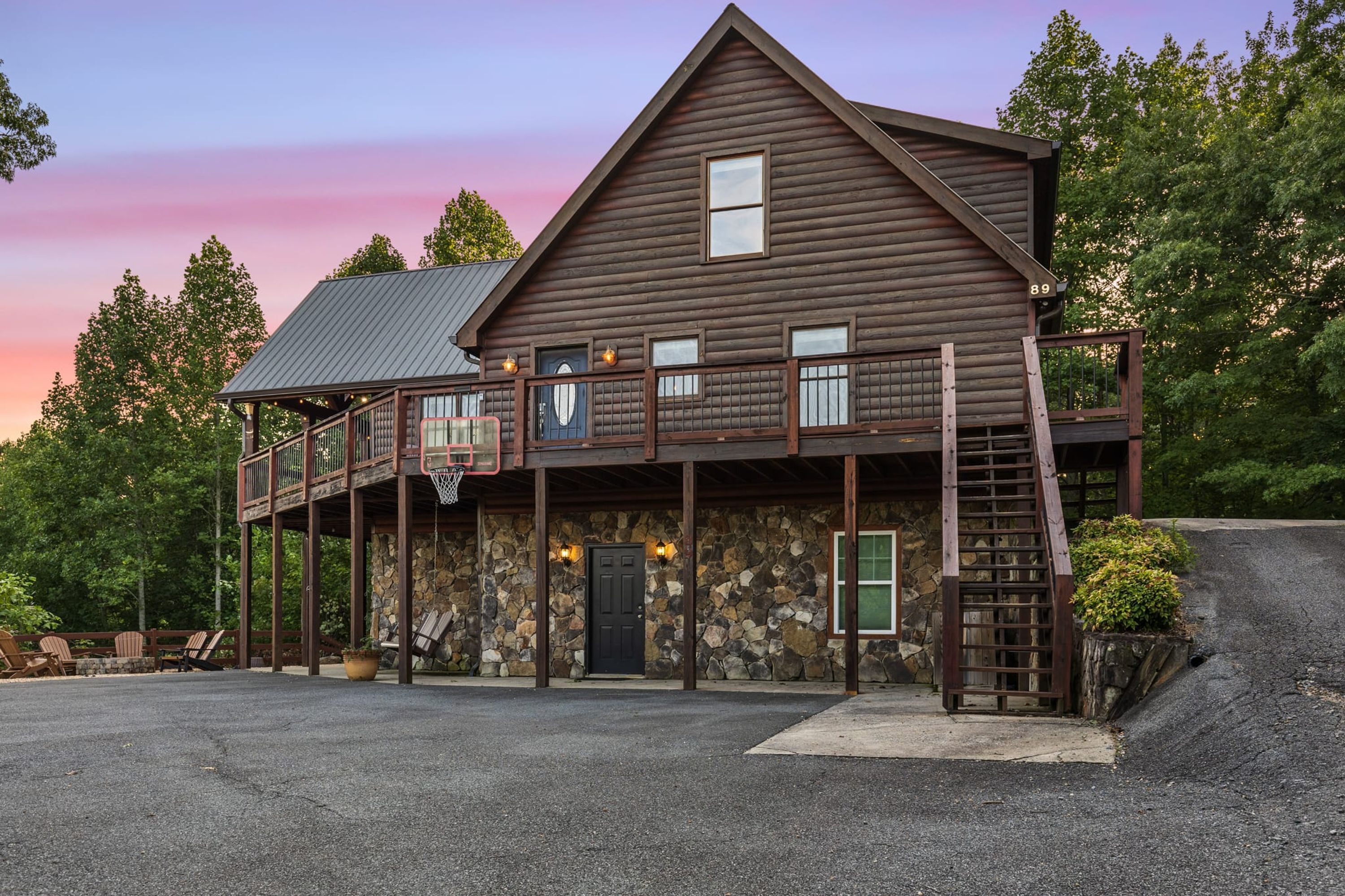 A two-story log cabin with a stone facade, a balcony, and a basketball hoop.