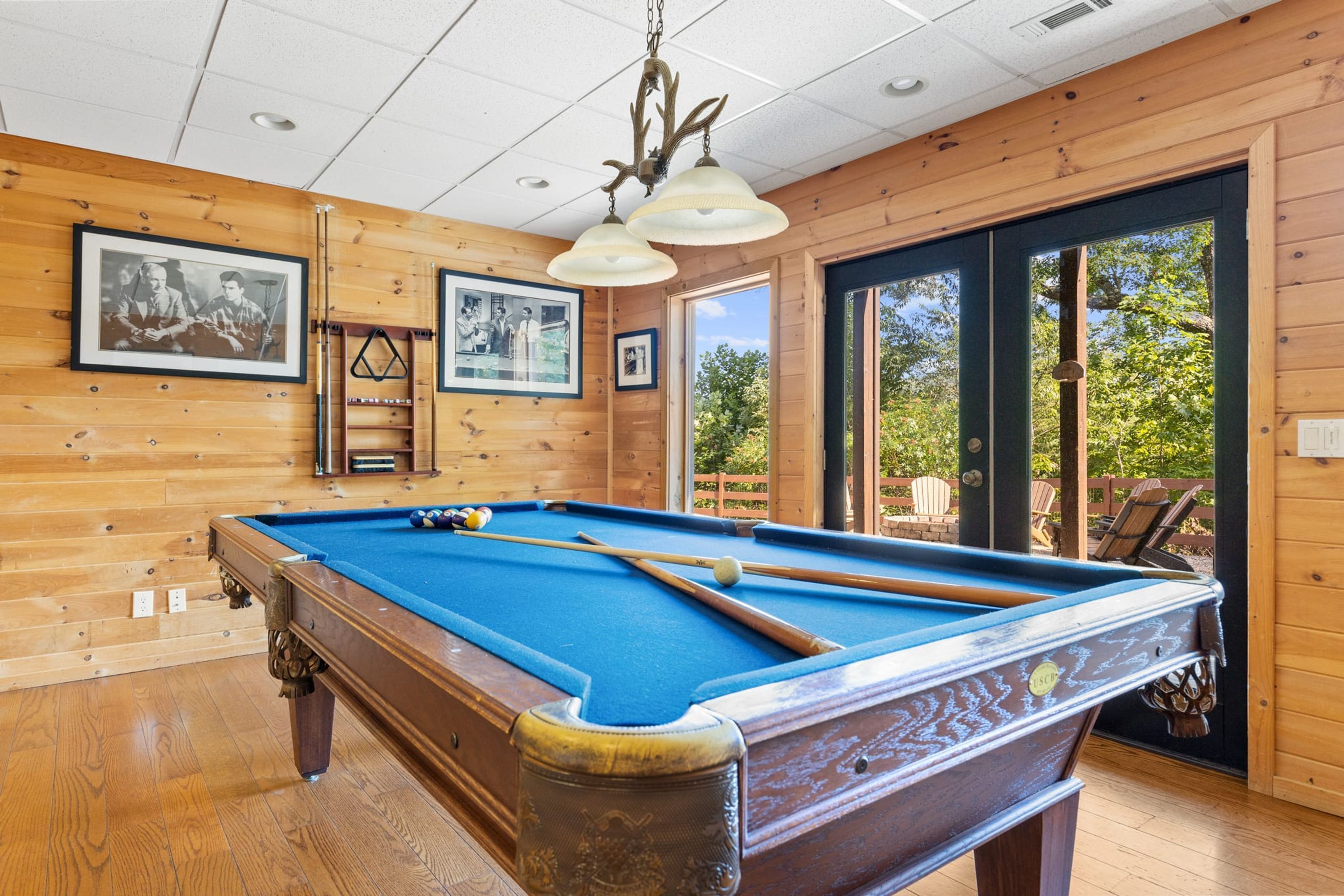 A pool table in a room with wooden walls and a ceiling light fixture.
