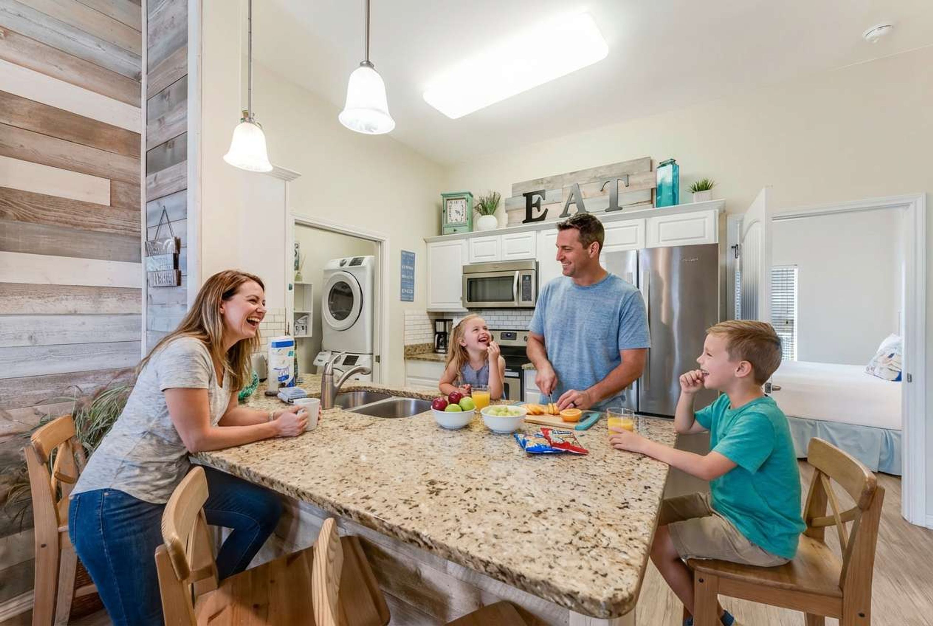 A modern kitchen with granite countertops, stainless steel appliances, and a dining area with wooden chairs.