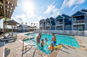 A swimming pool area with a pool, lounge chairs, and a building with balconies. - Walk to Beach Private Hot Tub Pool Dog Friendly (Corpus Christi)