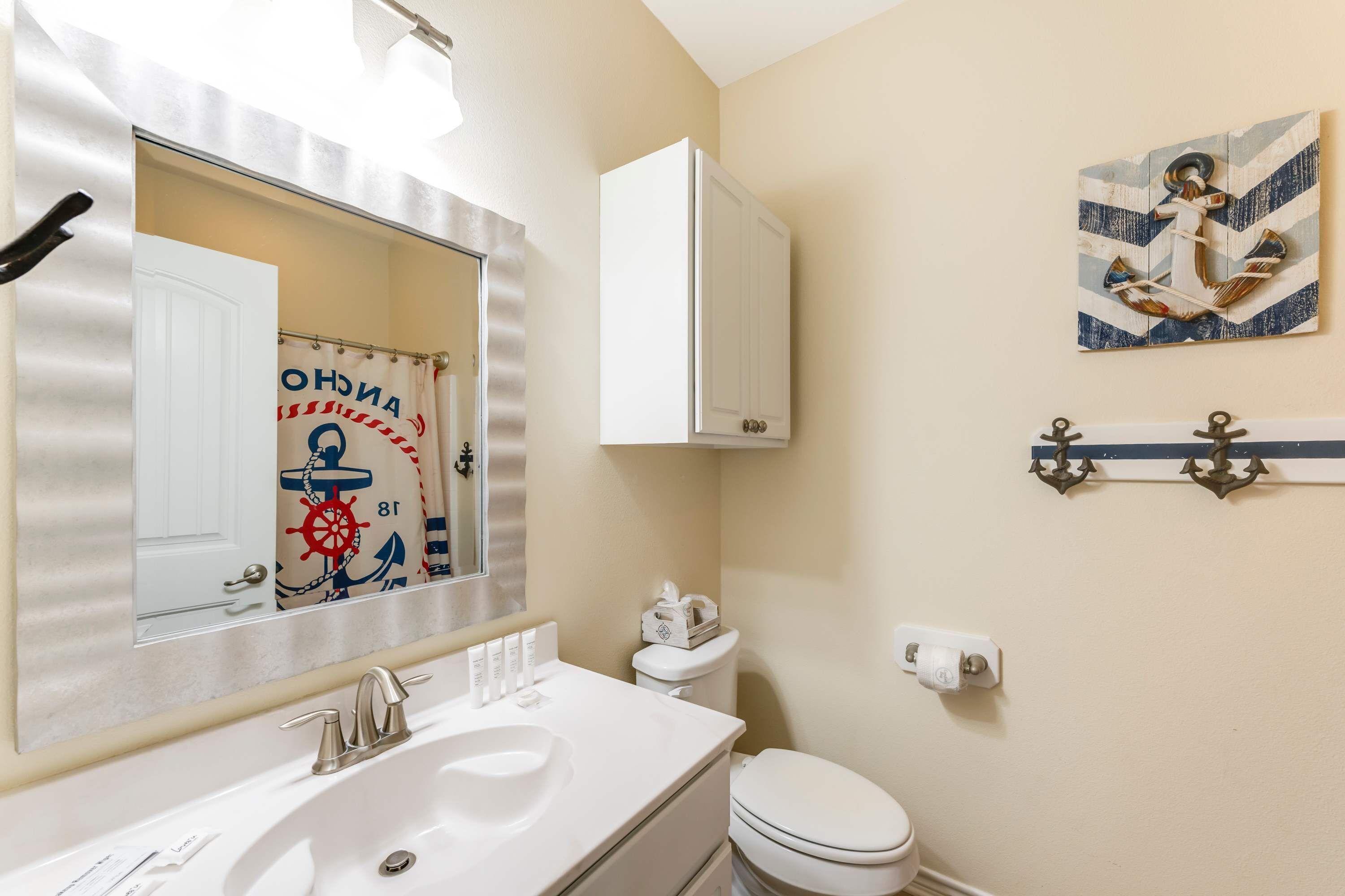 A bathroom with a white sink, a mirror, a toilet, and a cabinet.