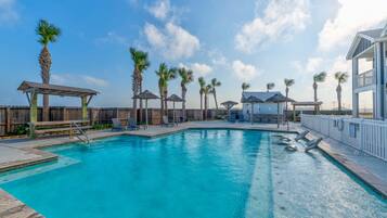 A swimming pool with lounge chairs and palm trees.
