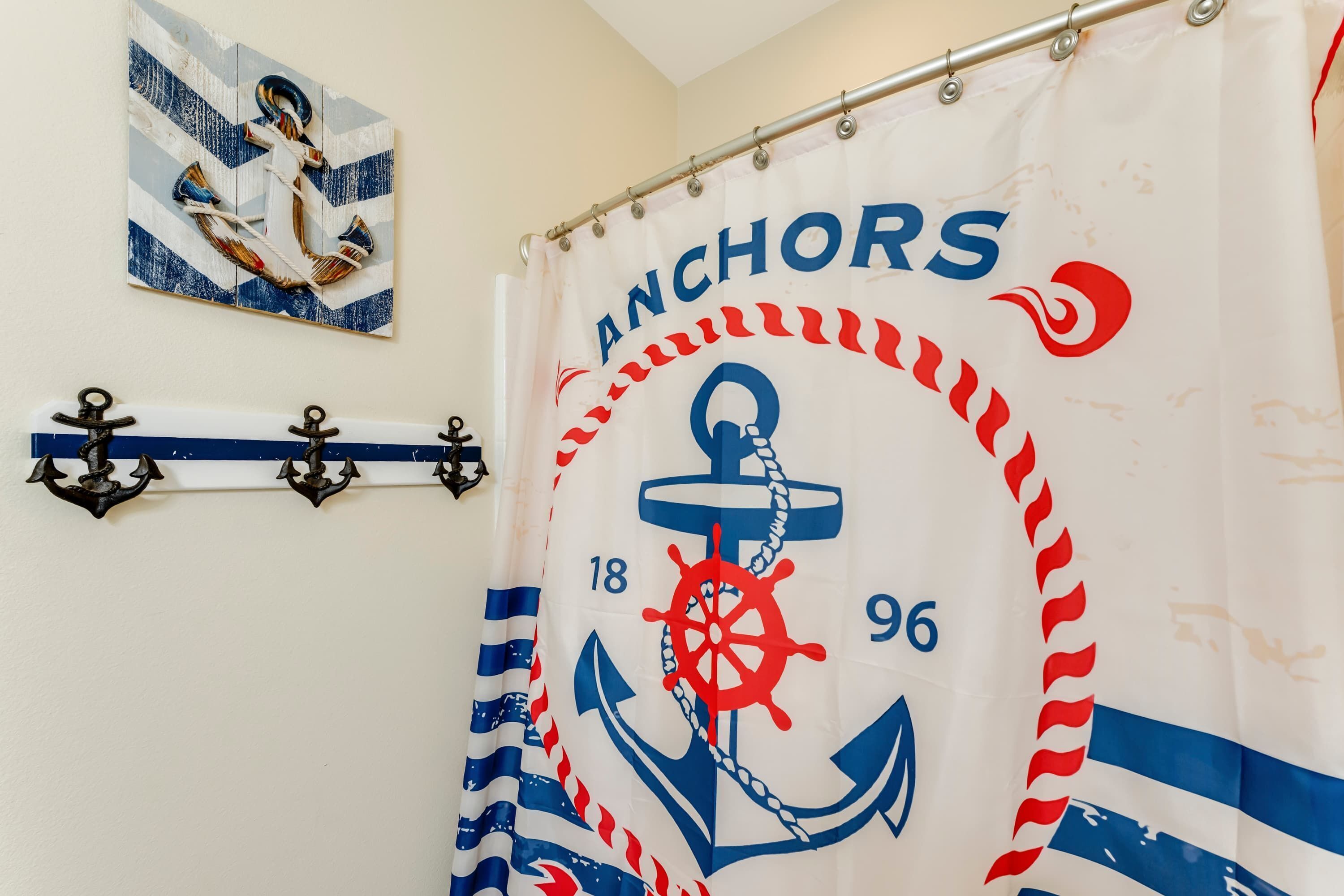 A bathroom with a nautical-themed shower curtain featuring an anchor and the word 'ANCHORS'.