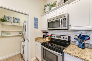 A kitchen with white cabinets, a stainless steel microwave, an oven, and a coffee maker. There are decorative items on the shelves and a sign on the wall. - Walk to Beach Private Hot Tub Pool Dog Friendly (Corpus Christi)