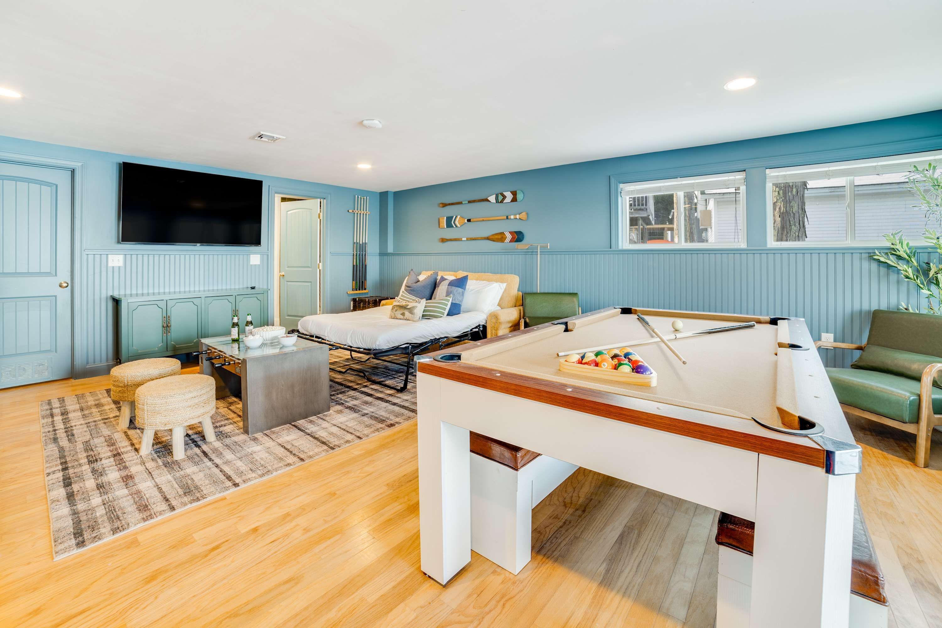 A room with a pool table, a bed, a sofa, and a television.