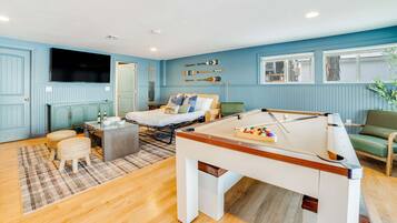 A room with a pool table, a bed, a sofa, and a television.