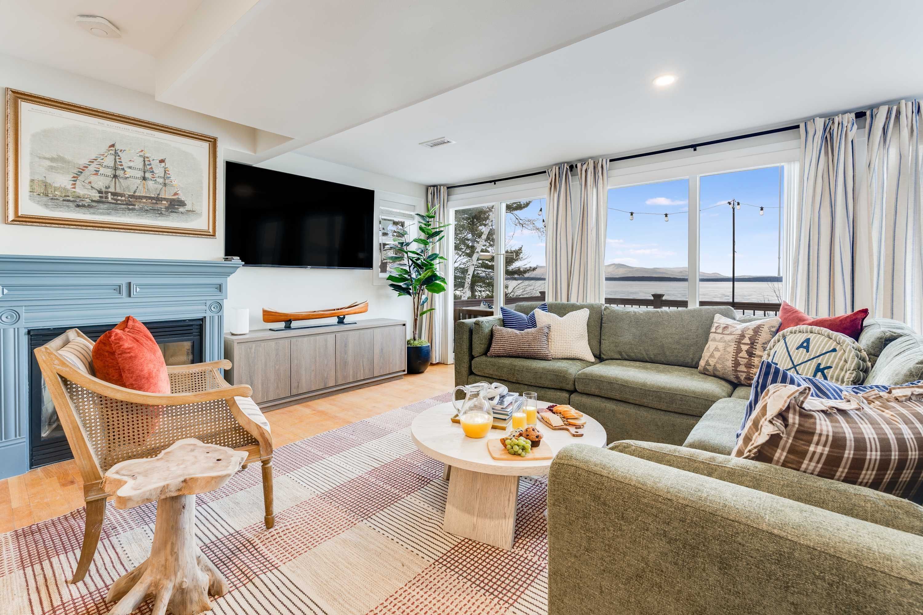 A living room with a fireplace, a television, a sofa set, and a dining table with breakfast items.
