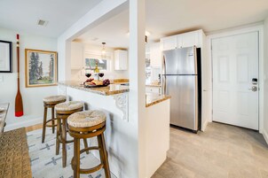 Una cocina moderna con un refrigerador de acero inoxidable, una isla de cocina con taburetes y una zona de comedor con mesa y sillas.