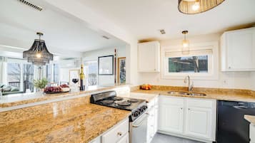 A modern kitchen with granite countertops, stainless steel appliances, and white cabinetry.