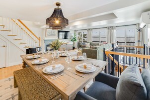A dining area with a wooden table set for a meal, a staircase, and a view of the outdoors.
