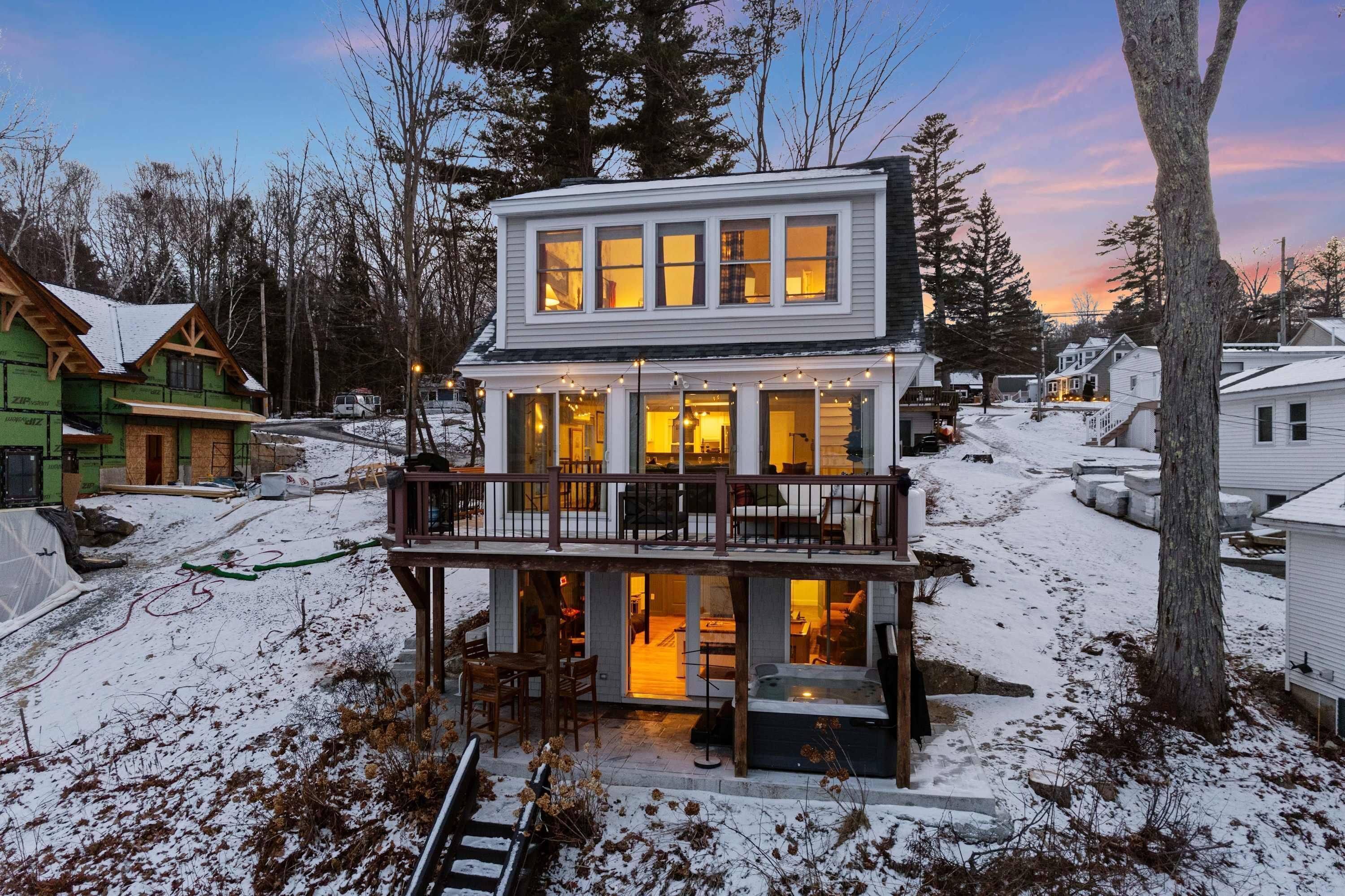 A two-story house with a balcony and a hot tub on the ground floor.